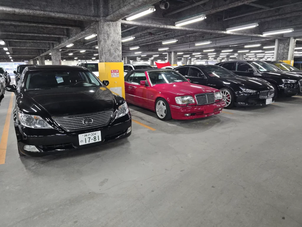 Czerwony Mercedes klasy S widoczny w hali obok innych aut, samochód z Japonii