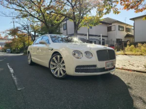 Biały Bentley Flying Spur widoczny z przodu na drodze, luksusowy samochód z Japonii
