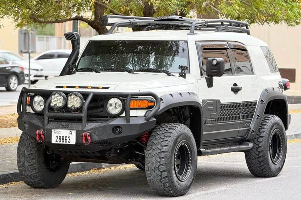 Biała Toyota FJ Cruiser widoczna z przodu z dodatkowymi lampami i oponami terenowymi, auto z Dubaju